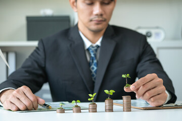 Businessman with coin stack at his office as sustainable money growth investment or eco-subsidize....
