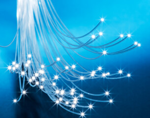 Bundle of optical fibers with lights in the ends. Blue background.