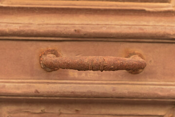 A fragment of an old wooden door with a metal handle covered with rust.