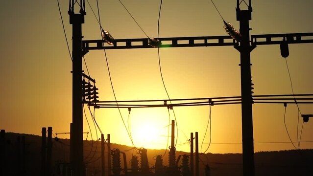 High voltage electric transformer station and distribution network at sunset. Power transmission lines on supports with ceramic insulators and transformers at large electrical distribution substation
