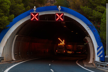 Tunnel on a highway with light signs warning of closed lanes, with a maintenance vehicle inside...