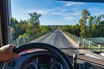 View from the driving position of a truck of a conventional two-way road over a narrow bridge where...
