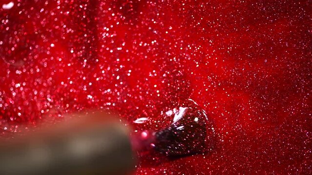Red glitter nail polish UV gel background with brush. Nailpolish liquid surface, red shellac UV gel brush, varnish, manicure concept. Manicure salon, shellac texture background, backdrop. Top view. 