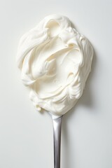 Close up of white whipped cream on a spoon with a white background.