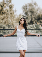 Photograph, portrait of a beautiful young brunette Armenian girl in a white dress in a park on the street outdoors.