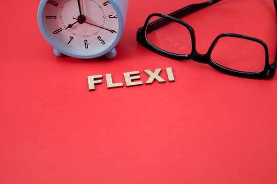 Concept of flexible time. The letter FLEXI on the red background with an alarm clock and eyeglasses. Copy space for text, message, information, etc.