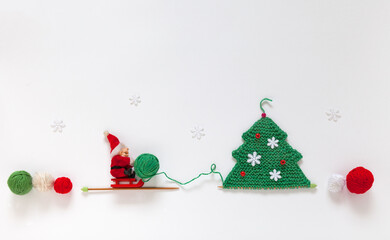 Merry Christmas and Happy New Year: cheerful Santa carries a ball of green woolen yarn to a...