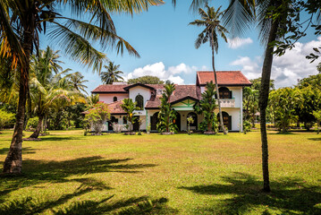 Old colonial house building in tropical garden with palm trees
