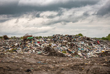 Pile of garbage on the landfill under storm clouds
