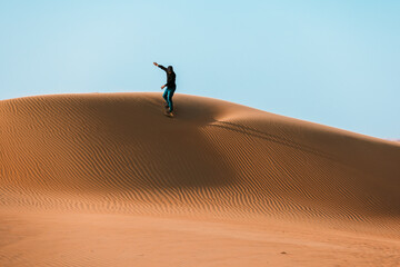 High quality stock photo of a man sliding down with a sand board in a dune in the Sultanate of Oman.