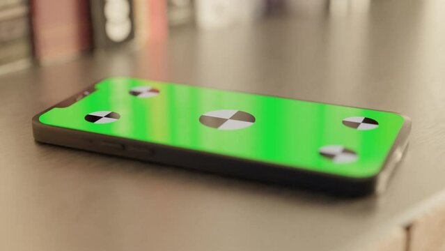 Side view of a Smartphone with a Green Screen on the table with books