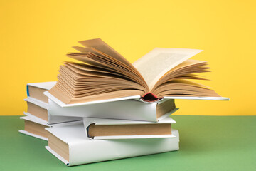 Books stacking. Open hardback books on wooden table and green background. Back to school. Copy space for ad text.