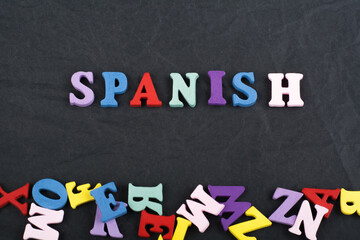 SPANISH word on black board background composed from colorful abc alphabet block wooden letters, copy space for ad text. Learning english concept.