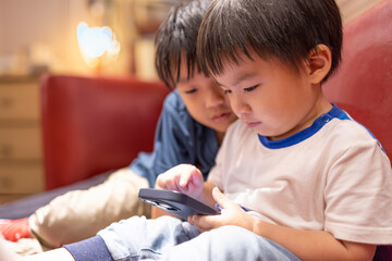 Happy kids  playing online game with mobile phone in living room - obrazy, fototapety, plakaty