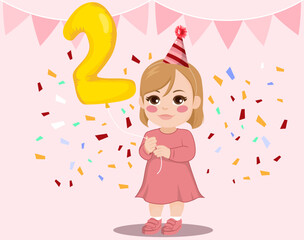 Cute full body baby girl standing with confetti and holding big golden color number two helium balloon on pink background. Child with party hat celebrating 2n anniversary birthday