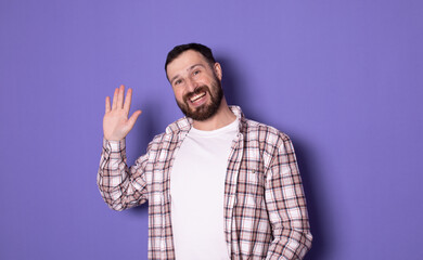 Portrait of happy handsome bearded man saying hi, waving raised hand informal greeting, nice to...