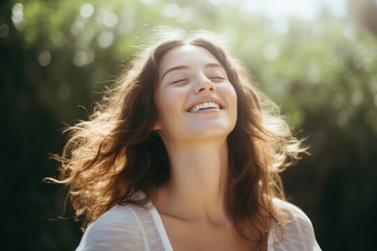 Portrait of a young woman smiling with closed eyes of Caucasian ethnicity with long curly hair in nature