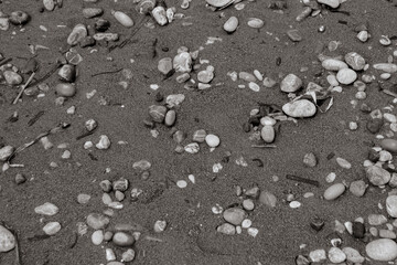 Abstract background beach sand with pebble rocks on the ground at Paralia Ixia beach off Rhodes city in black and white