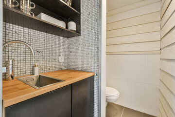 a kitchen with wood counter tops and white tiles on the wall behind it is a sink, fauced by an open...