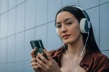 relaxed young woman with headphones on blue wall