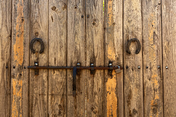 Puerta antigua de madera con cerrojo y herraduras.