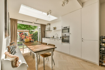 a kitchen and dining area in a house with wood flooring, white cabinets and an oven on the wall