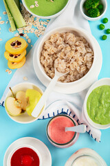 Bowls with healthy baby food on blue background.