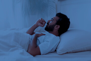 Side View Of Sick Indian Man Coughing In Bed In The Night