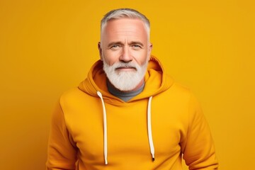 Middle-aged Caucasian man in yellow sweatshirt on ywllow background smiling, cheerful and pleasant. - obrazy, fototapety, plakaty