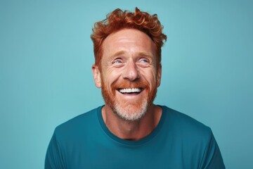 Middle-aged red-haired man on blue background smiling - obrazy, fototapety, plakaty