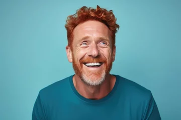 Gardinen Middle-aged red-haired man on blue background smiling © Eva Corbella