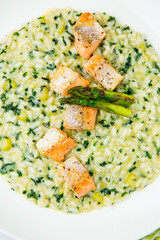 rice porridge with greens, artichoke and pieces of red fish, top view