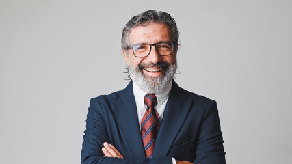 Middle-aged businessman in glasses with gray hair, laughing looking at the camera, isolated on gray background in the studio - obrazy, fototapety, plakaty
