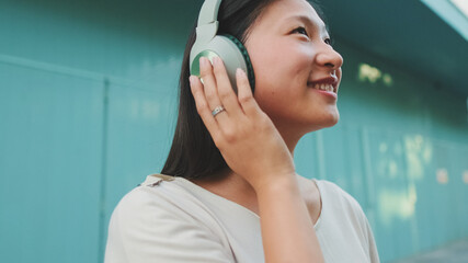 Happy beautiful brunette girl in headphones dressed in casual clothes, listens to music and singing along