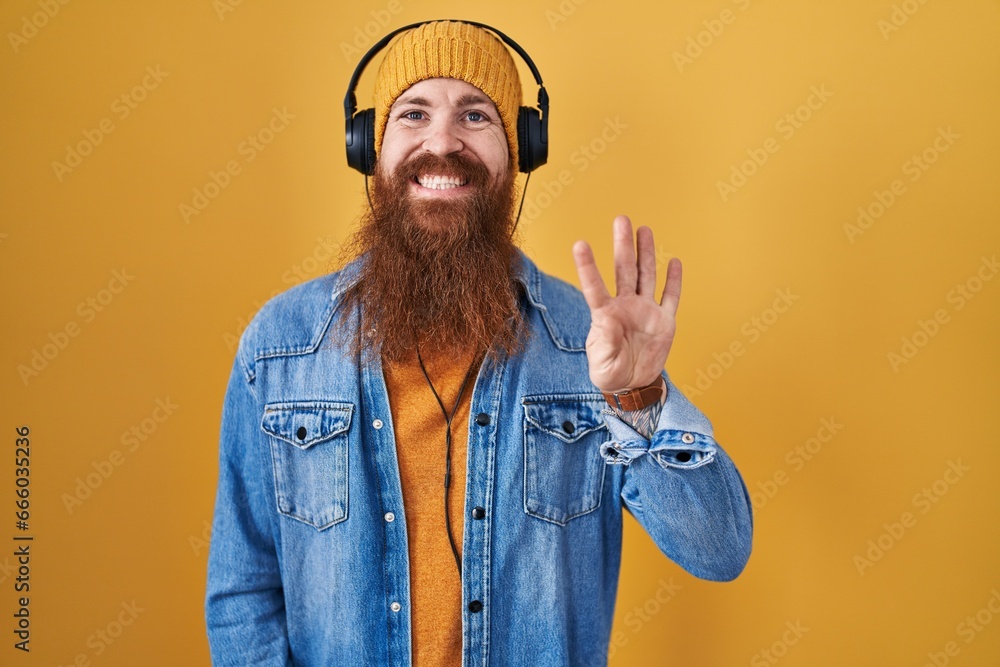 Sticker Caucasian man with long beard listening to music using headphones showing and pointing up with fingers number four while smiling confident and happy.