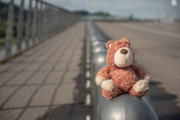 A plush bear toy is sitting on a bridge