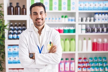 Handsome hispanic man working at pharmacy drugstore happy face smiling with crossed arms looking at the camera. positive person.