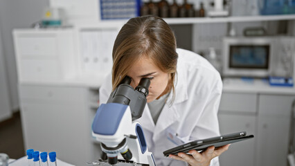 Serious young blonde female scientist engrossed in discoveries, meticulously analyzing samples...