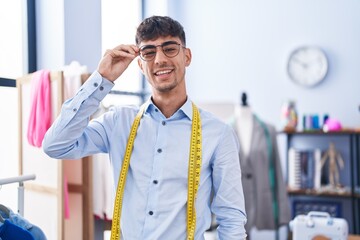 Young hispanic man tailor smiling confident standing at tailor shop