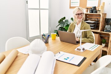 Young blonde woman architect using laptoo smiling at office