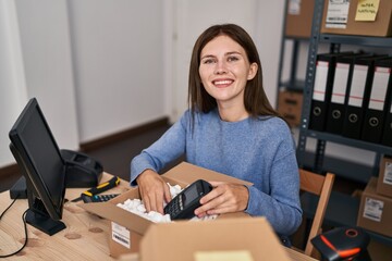 Young blonde woman ecommerce business worker packing data phone on cardboard box at office