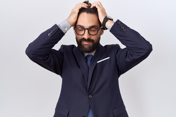 Hispanic man with beard wearing suit and tie suffering from headache desperate and stressed because pain and migraine. hands on head.