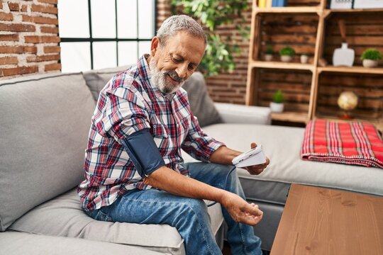 Senior grey-haired man measuring pulse using tensiometer at home