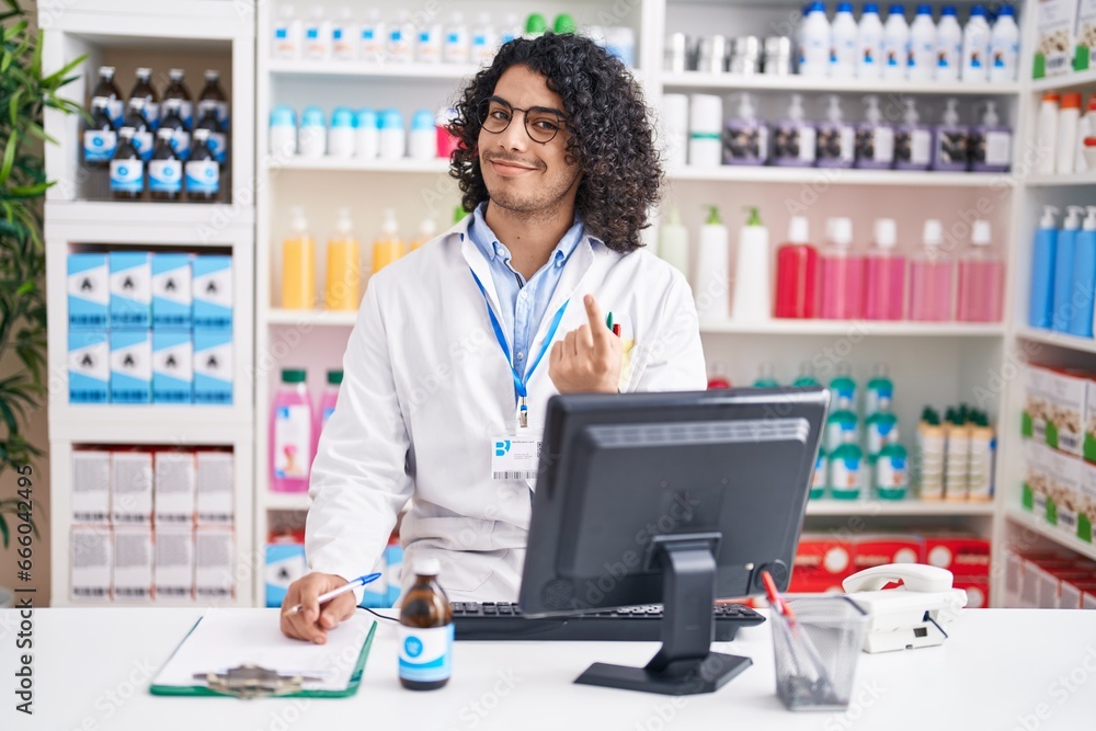 Sticker hispanic man with curly hair working at pharmacy drugstore beckoning come here gesture with hand inv