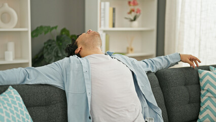 Young latin man sitting on sofa relaxing at home