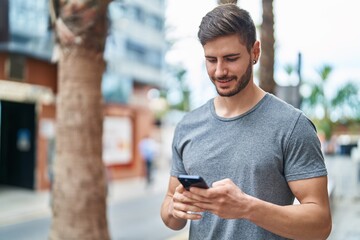 Young caucasian man smiling confident using smartphone at street