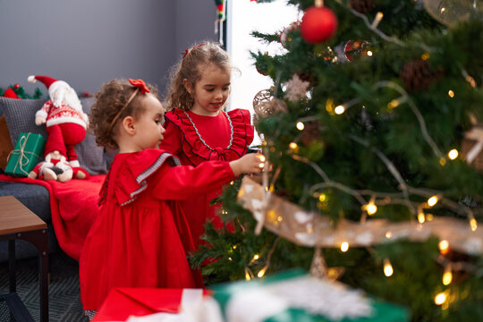 Adorable girls decorating christmas tree at home