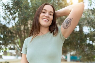 Young beautiful woman smiling confident relaxed with hand on head at park