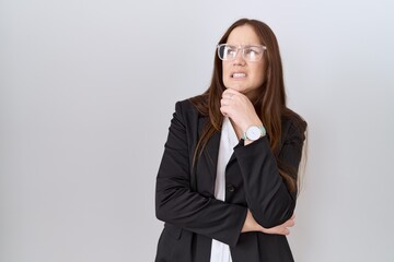Fototapeta na wymiar Beautiful brunette woman wearing business jacket and glasses thinking worried about a question, concerned and nervous with hand on chin