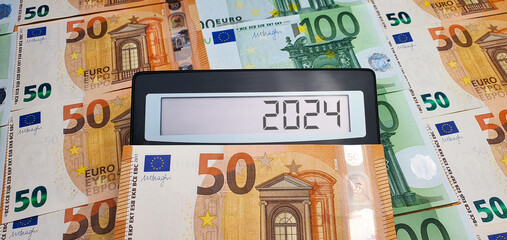 New challenges in 2024. Calculator on the background of 50 and 100 euro banknotes. Inflation, economic crisis, elections, war, recession, bankruptcy, cost of living, bills, poverty, migrants - obrazy, fototapety, plakaty